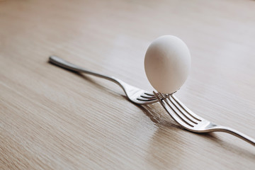 one whole white egg on 2 forks on wooden background