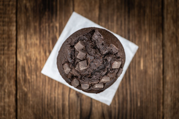 Old wooden table with fresh Chocolate Muffins (close-up shot; selective focus)