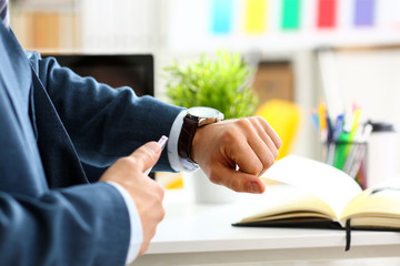 Man in suit and tie check out time at silver wristwatch closeup. Show and point with finger waste...