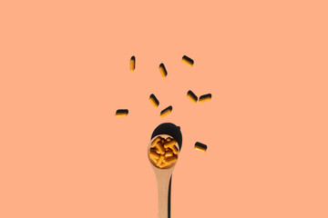 wooden spoon with turmeric curcumin capsules on beige background