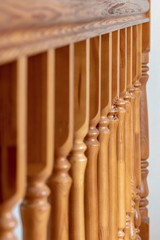 Element of a wooden interior staircase. Wooden baluster close-up.