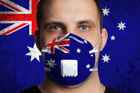Young man with sore eyes in a medical mask painted in the colors of the national flag of Australia. Coronovirus disease  COVID-19 concept.  Man is afraid of getting the flu