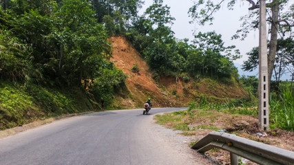 a motorcycle driving on a winding mountain road in northern Vietnam.