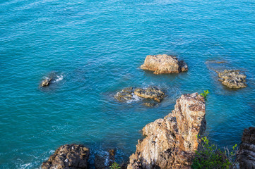Top view from the cliff on the sea rocks and surf with waves
