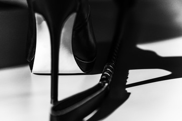 Female domination concept. BDSM sex toys: sexy black fetish high heels and riding crop. Adult sex toys for role play - obrazy, fototapety, plakaty