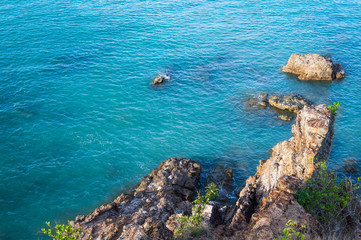 Top view from the cliff on the sea rocks and surf with waves