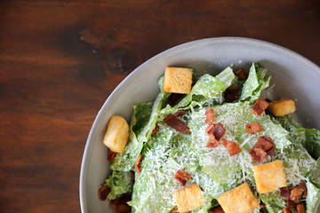 Caesar salad with crispy bread and bacon close up on wood background