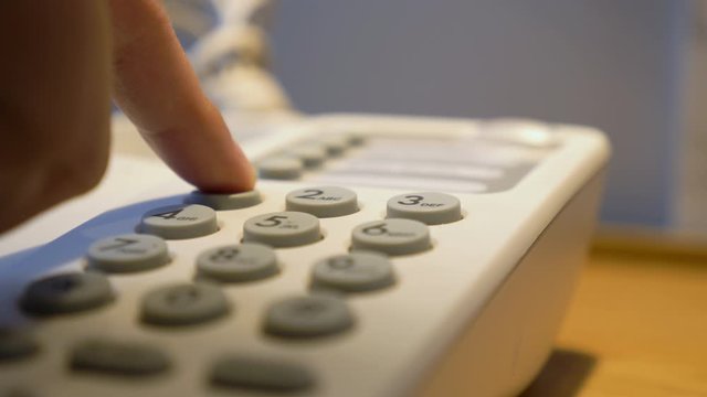 Hotel phone services concept.Closeup of hotel guests Pick up the phone holding and dialing phone number to room services.Vintage old telephone is a keypad.