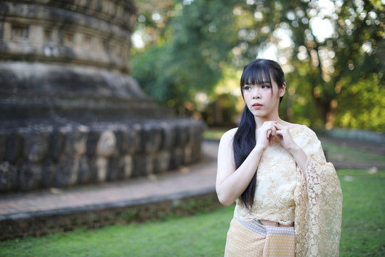 Portrait of Thai female with traditional Thai dress with temple background