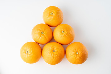 five fresh oranges lie in a triangle on a white background close-up, top view