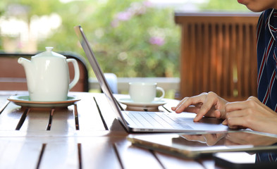 Closeup of woman's hand doing her work with notebook computer at home. Normal practice by work-from-home, social distancing during COVID-19 outbreak around the world. 