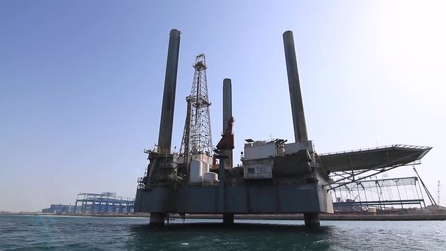 Sea oil drilling platform at sea in the dry dock area of Bahrain. Camera pans from a boat along the platform providing a dynamic moving image.