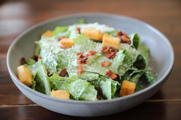 Caesar salad with crispy bread and bacon close up on wood background