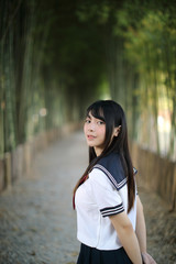 Portrait of beautiful Asian japanese high school girl uniform looking with bamboo forest background