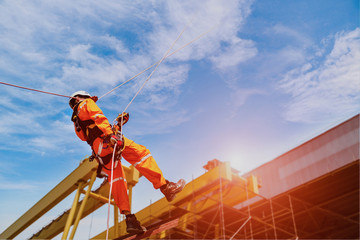 Workers safety uniform, Rope access at construction wearing full safety body harness with helmet protection hanging upside on roof factory and crane background..