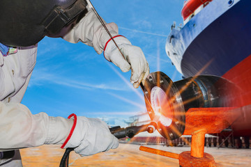 Ship repair industry workers Welding process with spark light wear equipment protective in shipyard and cargo ship background.
