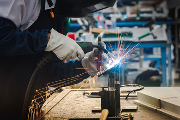 The welder is welding the metal parts in the automobile assembly plant and practicing the skills of...