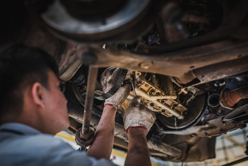 The mechanic is working to check the cars that work in the car service center with a forklift. Car repair and maintenance