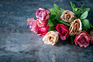 Artificial antique roses on stony background.