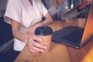 Young woman smile and hold cup of coffee while working with laptop in quarantine.