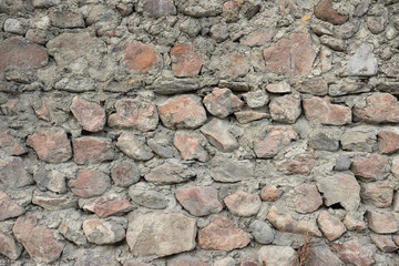 old unfinished wall of stones of various shapes and cement.