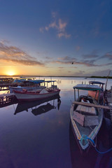 jetty with small boats used for fishing in a beautiful sunset. Landscape concept.