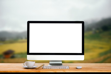 Workspace with computer, keyboard, coffee cup and Mouse with Blank or White Screen Isolated is on the work table at the mountain and trees front view background.