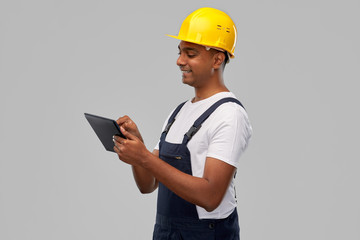 profession, construction and building - happy smiling indian worker or builder in helmet with tablet pc computer over grey background
