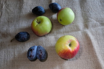 beautiful apples and plums on a light background of burlap on the fruit, dents are visible during transportation