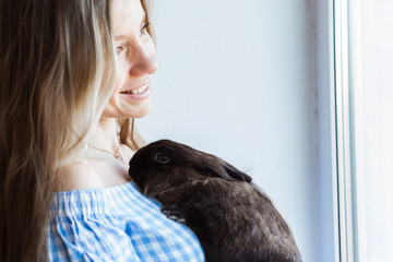 Pet and Easter concept - Attractive girl hugging brown rabbit at home.