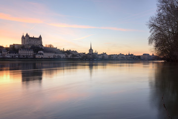 Panorama view of Saumur town from across the Loire river at sunset, with the medieval castle and the old town with Saint-Pierre church