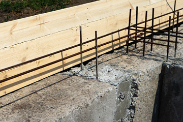 Formwork for the foundation of the house. Closeup of house foundation made from concrete shuttering blocks filled with mortar and reinforcement bars.