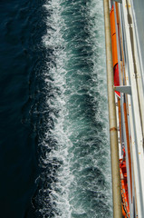 View from the top deck onto wake of cruiseship or cruise ship liner at sea and starboard side of...
