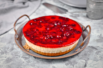 Whole round cheesecake gazed with cherry fruit topping on iron tray