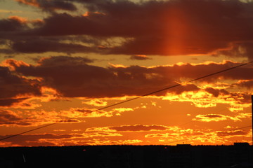 Sun below the horizon and clouds in the fiery dramatic orange sky at sunset or dawn backlit by the sun. Place for text and design.