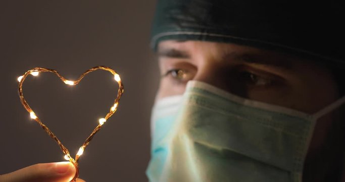 Curare i pazienti affetti da Coronavirus. Medico dona una speranza con il cuore fatto da luci led.