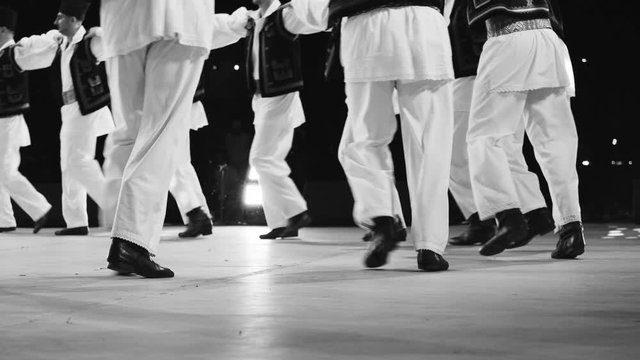 Traditional romanian folklore dancers in traditional costumes dancing on stage in slow motion and black and white footage
