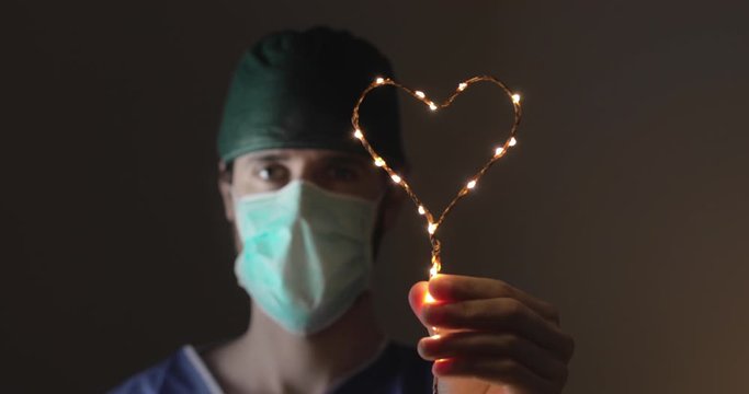 Infermiere dopo il turno a curare i pazienti da Coronavirus in ospedale tiene in mano un cuore luminoso per dare forza a chi sta lottando.