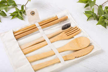 Set of Eco friendly bamboo cutlery in a case on wooden white background. Sustainable lifestyle. Plastic free concept. Close up