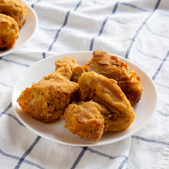 Tasty homemade oven baked fried chicken on a white plate, side view. Close-up.