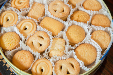 Tin box with Danish butter cookies on grey table . cookies in sheleznoy bank . Overhead view of the cookies in a circle shaped container over light . Sweet cookies in a Round box .