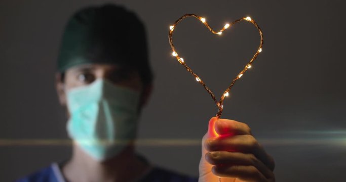 Anestesista a fine turno in ospedale tiene in mano un cuore luminoso come simbolo di speranza per i pazienti che lottano contro il Coronavirus covid-19