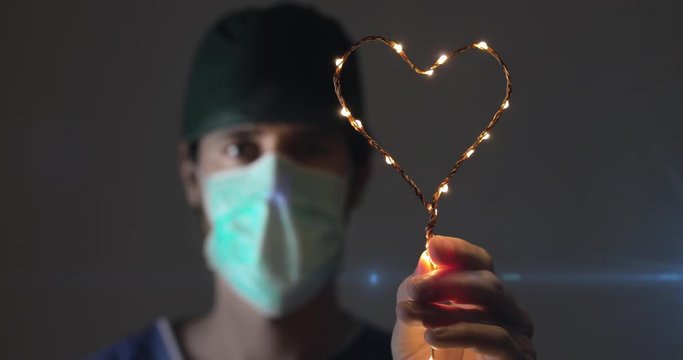 Medico giovane tiene in mano un cuore luminoso in ospedale per curare i pazienti affetti da Coronavirus covid-19. Hashtag ce la faremo Italia.