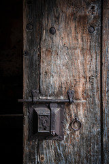 Ancient rusty steel lock bolt with a key hole installed on an old wooden door from medieval age