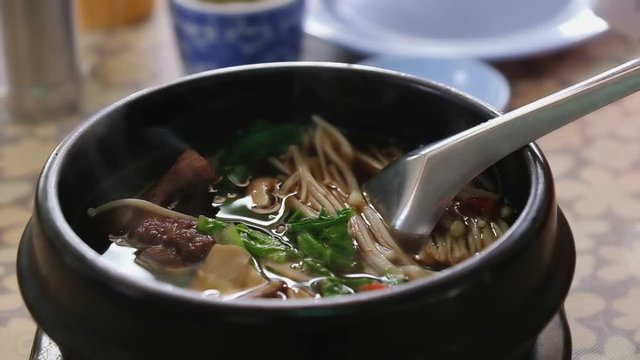 Slow motion , close up of "Bak kut teh soup" with smoke ,  pork rib dish cooked in broth popularly served in Thailand.