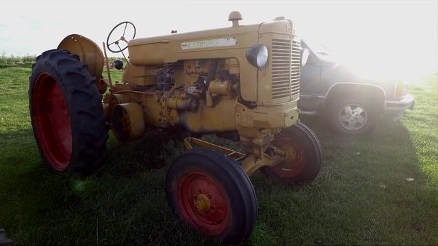 Twenty seconds of an antique tractor and truck on a quiet farm at sunset