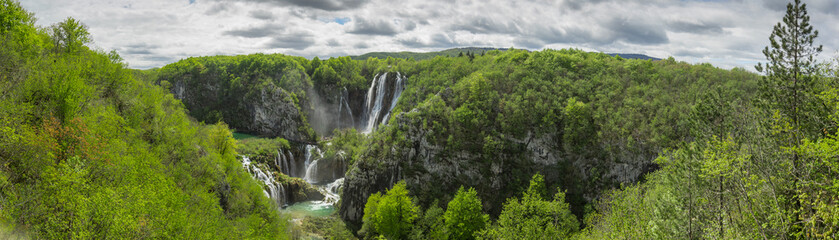 Fototapeta na wymiar Panoramic view of the biggest waterfall called veliki slap in plitvice lakes, croatia on a cloudy spring day. Big waterfall surrounded by lush greens in springtime.