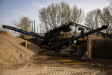 Machine sorting sand and gravel. Excavator and conveyer at the quarry