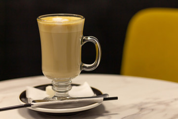Latte in a glass mug with a straw on the table