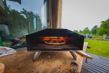 Interior view of a pellet fired home pizza oven ina garden. Fresh delicious pizza is seen inside the oven